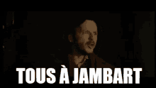 a man with a beard is screaming in a dark room with the words `` tous a jambart '' written above him .