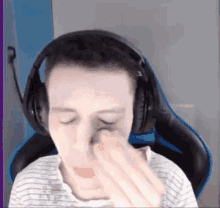 a man wearing headphones and a striped shirt is rubbing his nose .