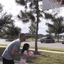 a man and a little girl are playing basketball in front of a basketball hoop that says " hop " on it