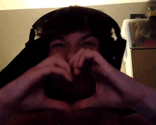 a man wearing headphones making a heart shape with his hands