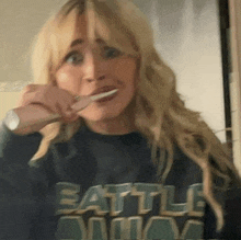 a woman brushing her teeth wearing a shirt that says battle