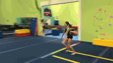 a girl in a black leotard is jumping on a trampoline