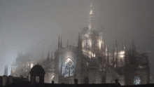 a foggy cathedral with a clock tower lit up