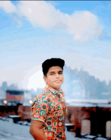 a young man in a colorful shirt stands in front of a city skyline