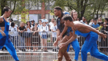 a group of people in blue jumpsuits are dancing in front of a crowd with a sign that says peace