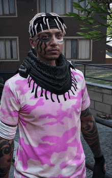 a man with tattoos on his face wears a pink shirt and a black scarf