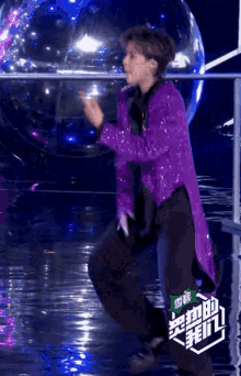 a person in a purple jacket is dancing in front of a clear ball