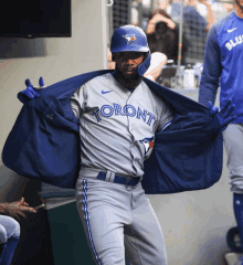 a toronto blue jays baseball player takes off his coat