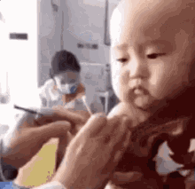 a baby is being examined by a doctor in a hospital room while a woman writes on a piece of paper .