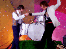 two men dancing in front of a ludwig drum