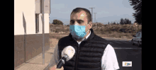 a man wearing a face mask is talking into a microphone