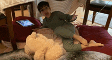 a young boy is laying on a bean bag chair next to a teddy bear and a tablet .