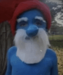 a person is dressed up as a smurf with a red hat and beard .