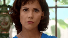 a close up of a woman 's face with a clock in the background