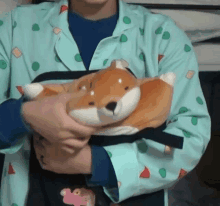 a person in a blue shirt is holding a stuffed animal in their arms .