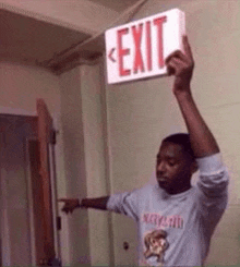 a man is holding a red and white exit sign in his hand .