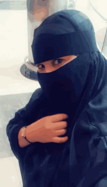 a woman wearing a black hijab covering her face looks at the camera .