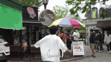 a man in a white shirt is standing in front of a colorful umbrella and a sign that says loooo .