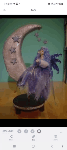 a fairy doll is sitting on a crescent moon with stars on it