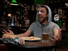 a man with a bandage on his nose sits at a table with a plate of food and a beer