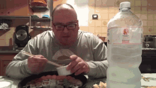 a man eating food with chopsticks next to a bottle of water that says ' acqua di sorgente ' on it