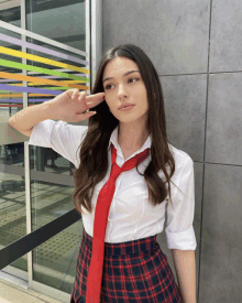 a girl wearing a white shirt and red tie is standing in front of a building