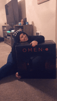 a woman laying on the floor holding a box that says omen on it