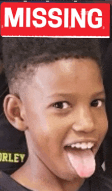 a young boy sticking his tongue out in front of a sign that says missing