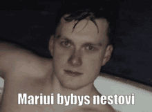 a man without a shirt is sitting in a bathtub with the words mariui bybys nestovi written above him .