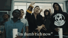 a group of young men are standing in front of a window and one of them says " i 'm dumb rich now " .