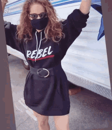 a woman wearing a black rebel hoodie and sunglasses