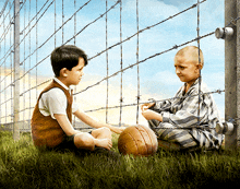 two young boys are sitting in front of barbed wire fence