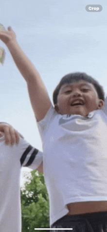 a boy wearing a white nike shirt is smiling with his arm up in the air