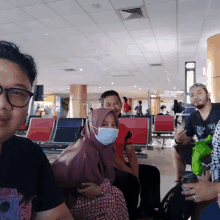 a woman wearing a face mask sits in a waiting room with other people