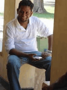 a man in a white shirt and blue jeans is sitting on a bench .