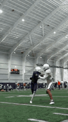 a football game is being played in an indoor stadium with a scoreboard showing a score of 29 to 0