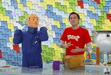 a man wearing a red shirt that says ' science ' on it stands next to a cartoon character