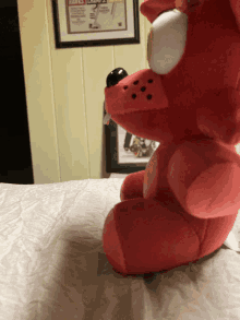 a red stuffed animal sits on a bed in front of a framed picture of a hockey player