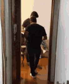 a man in a black shirt is walking through a doorway holding a child