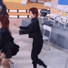 a woman in a black jacket and pants is dancing