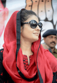 a woman wearing sunglasses and a red scarf looks down