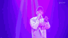 a man singing into a microphone in front of a purple background with the word genie on it