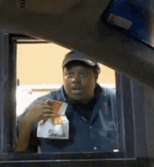 a man in a mcdonald 's drive thru window is holding a bag of chips