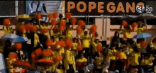 a crowd of people cheering in front of a pope gang sign