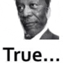 a black and white photo of a man in a suit with the words `` true '' below him .