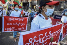 a group of people wearing masks are holding signs in foreign languages .