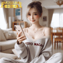 a woman wearing a toto macau sweater is holding a cell phone