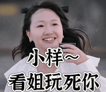 a woman in a white shirt is smiling and holding a cup with chinese writing on it