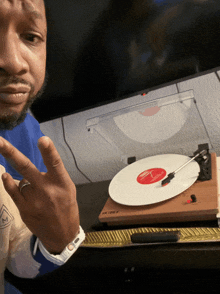 a man giving a peace sign next to a turntable