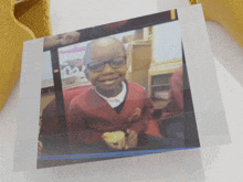 a picture of a young boy wearing glasses and a red shirt